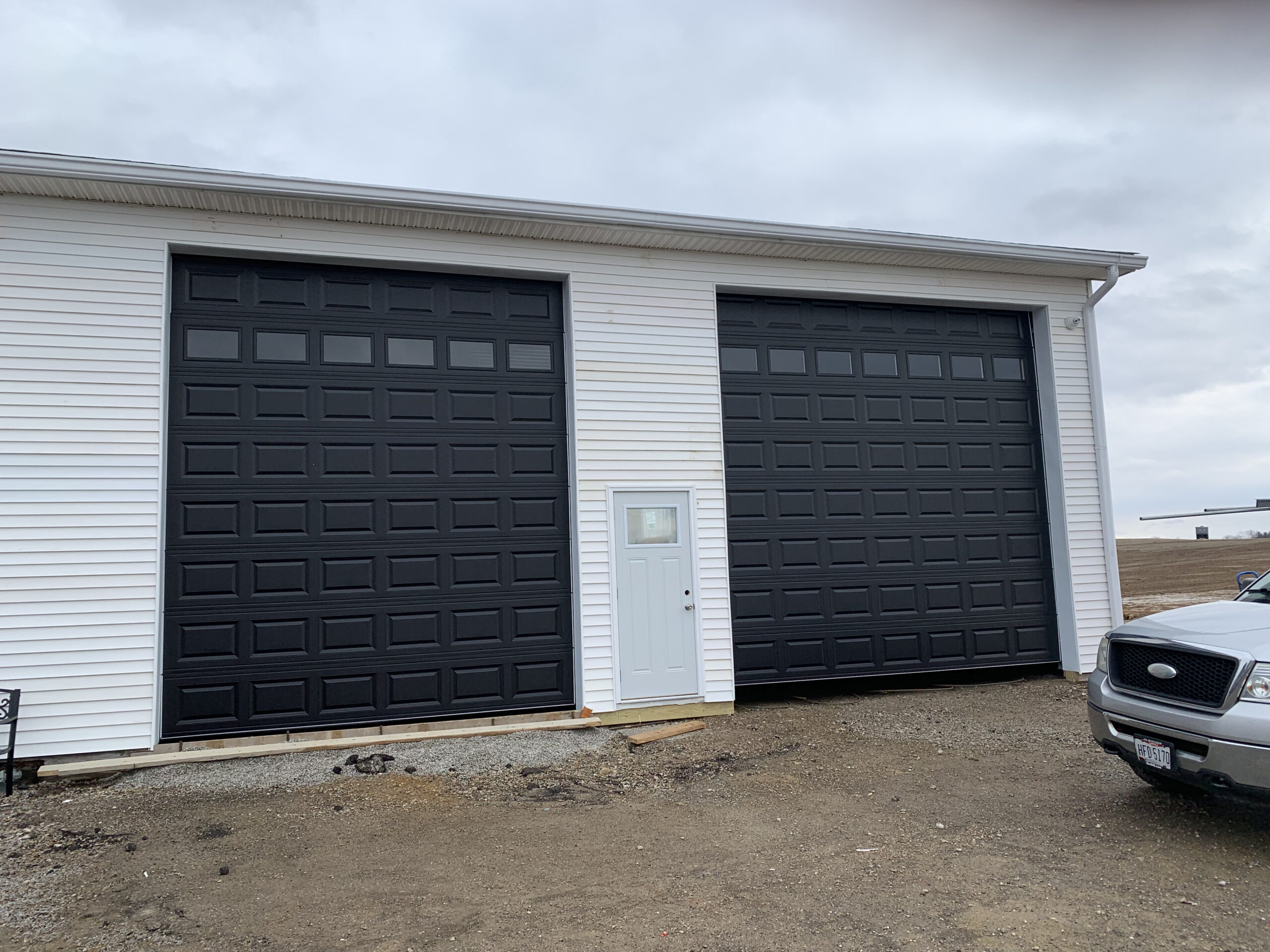 Tall Black traditional garage doors with windows. 